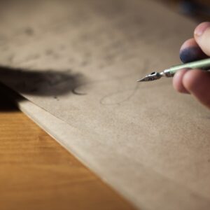 Close-up of a hand writing with a fountain pen on vintage paper, capturing the art of calligraphy.