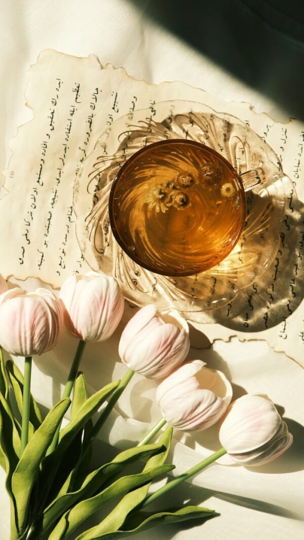 A refined flat lay of tea and tulips with elegant script, illuminated by natural sunlight.