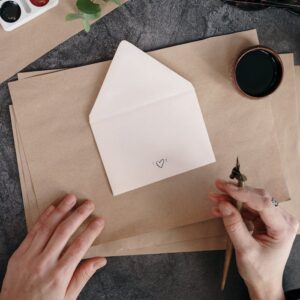 Elegant setup with calligraphy tools, envelope, and eucalyptus leaves on a table.